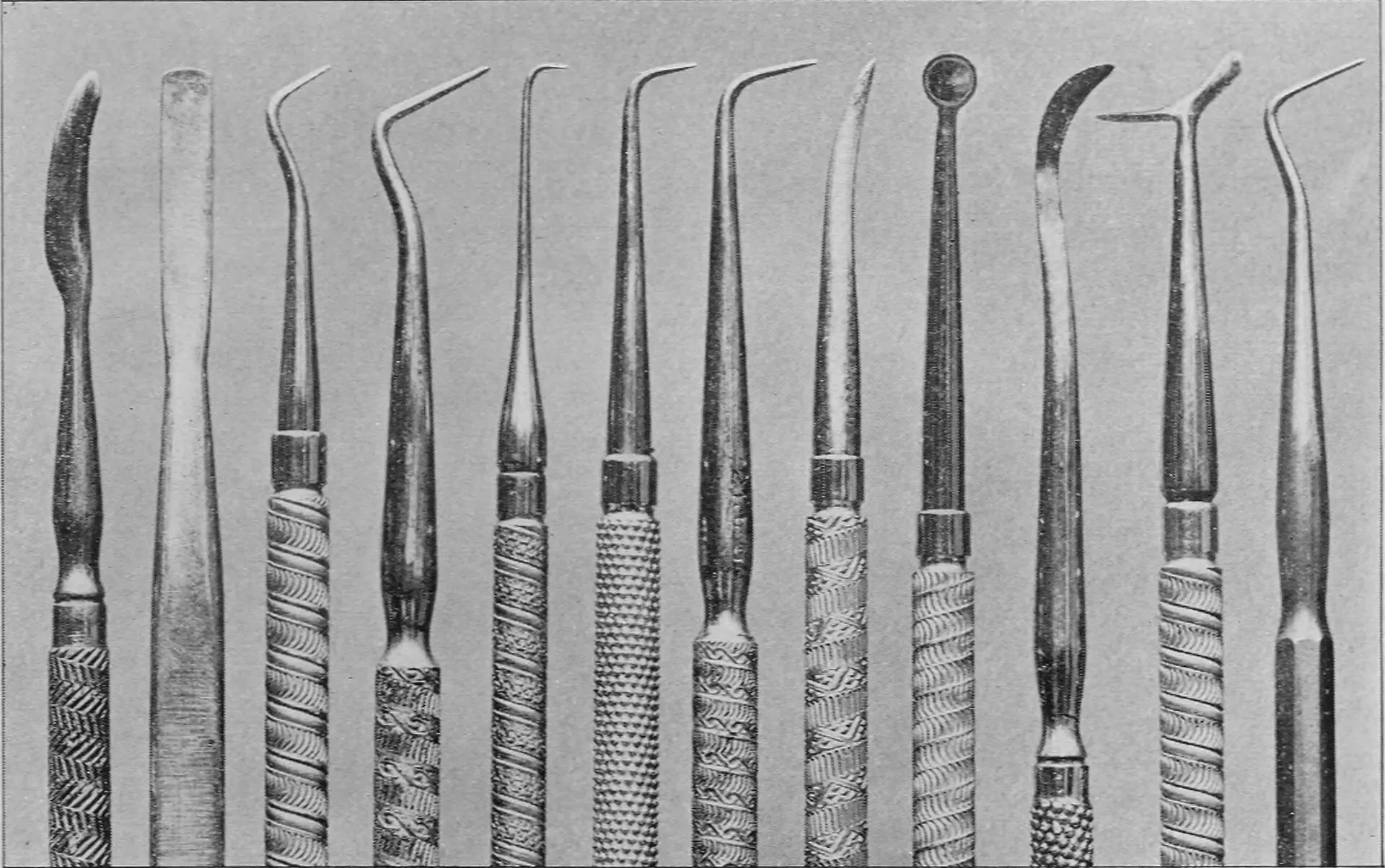 Fotografia antiga de doze instrumentos de escultura em cera, de cabo trabalhado, lado a lado